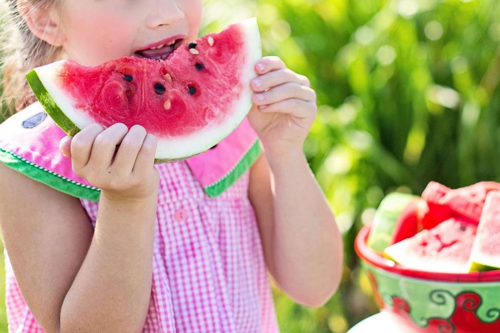 Niña comiendo sandia para una buena alimentación infantil