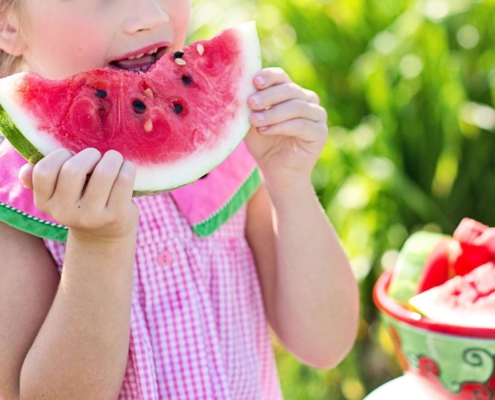 Niña comiendo sandia para una buena alimentación infantil